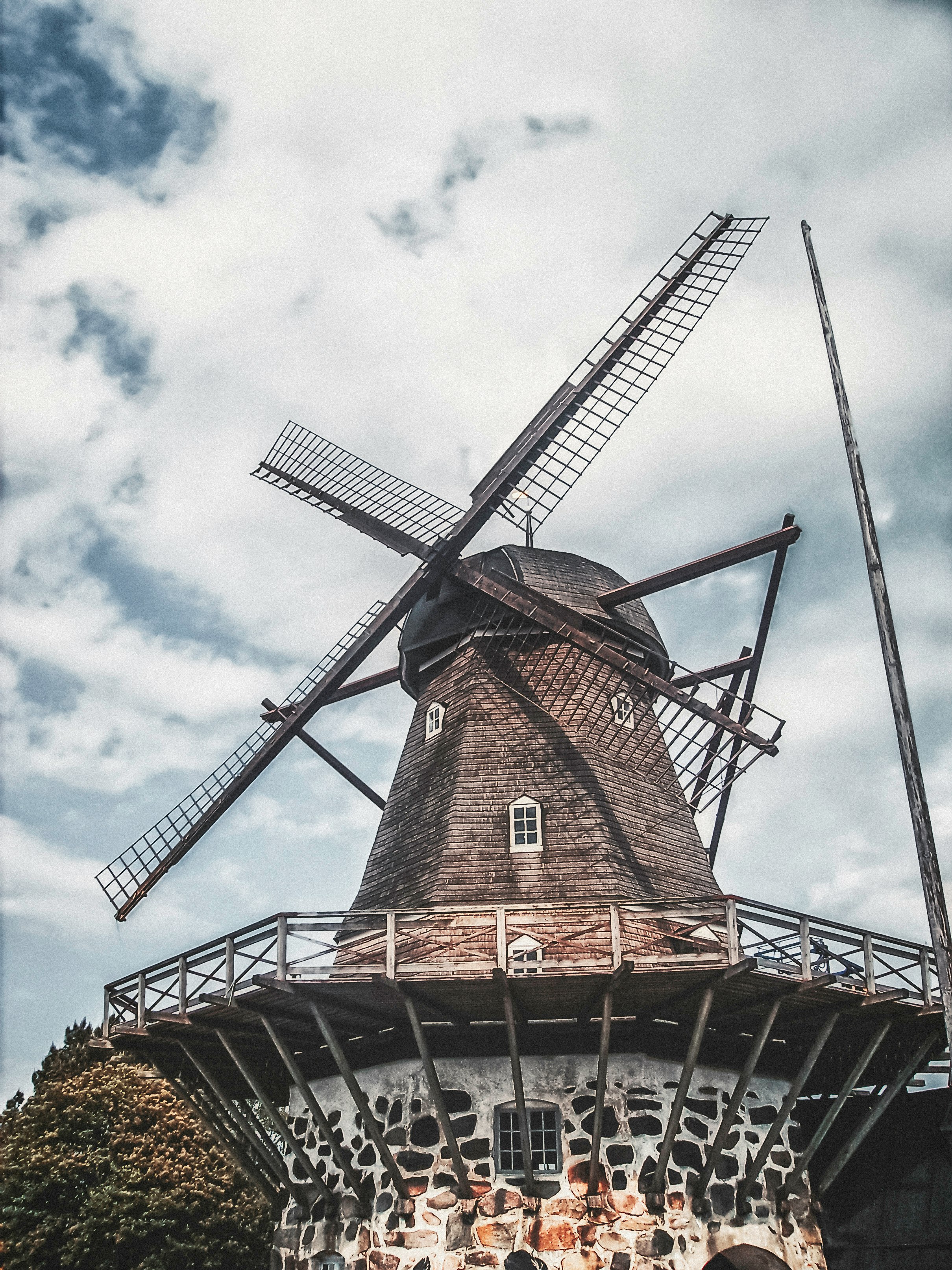 brown and black windmill under white clouds and blue sky during daytime